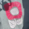 Druckergebnis einer Blume auf einem mintgrünen Pullover mit weißer und pinker Tetildruckfarbe gedruckt.