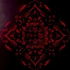Nahaufnahme: Holzschnitt in Neon-Pink auf schwarzem Hintergrund. Das Motiv ist ein symmetrisch aufgebautes Mandala aus Punkten und geschwungenen Linien, die in der Gesamtheit an Blüten erinnern.