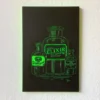 Holzschnitt hängt an der weißen Wand. Das Motiv zeigt in Neon-Grün auf schwarz drei Apothekerfläschchen mit den Etiketten „Poison“, „Elixir - Premium Quality“ und „Snake Oil“.