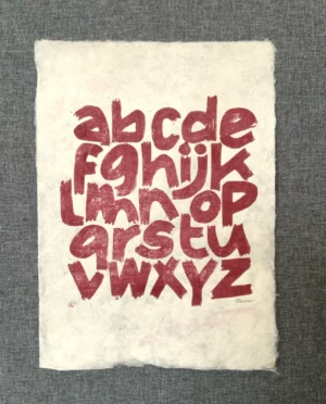 Linoldruck in dunkelrot auf Naturpapier - alle Buchstaben des Alphabets.