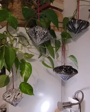 Selbst gebastelte Papier-Ornamente hängen an einer Pflanze.