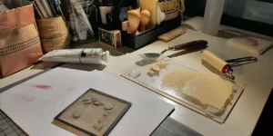 Schreibtischansicht mit Werkzeug, Farben und Druckplatte