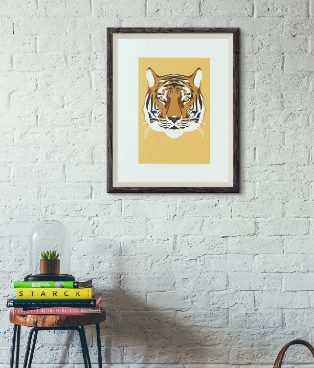 Gerahmer Druck "Tiger" an einer weißen Backsteinwand.
